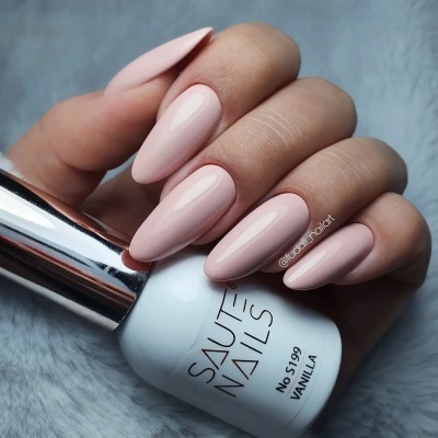 Unhas pintadas de rosa pálido segurando frasco de verniz de unhas branco com tampa cromada