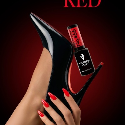 Verniz gel Victoria Vynn Devils Red No. 466, mão com unhas vermelhas segurando sapato de salto alto preto.
