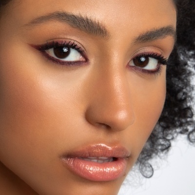 Rosto de mulher com maquilhagem de olhos roxos e lábios brilhantes