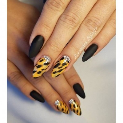 Unhas postiças pretas mate e amarelas com padrão animal print e pedras decorativas.