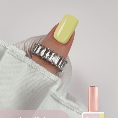 Unha pintada de amarelo suave com esmalte gel e anel prateado com pedras, texto purple PROFESSIONAL e frasco de esmalte