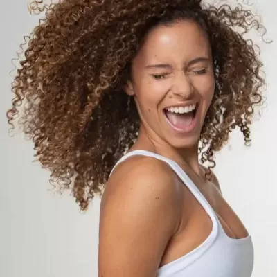 Mulher com cabelo encaracolado e top branco contra fundo branco