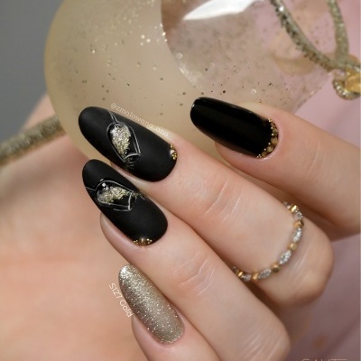 Unhas decoradas a preto mate e dourado brilhante com acessórios e anéis