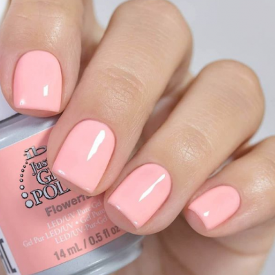 Unhas pintadas de rosa claro com frasco de verniz gel.