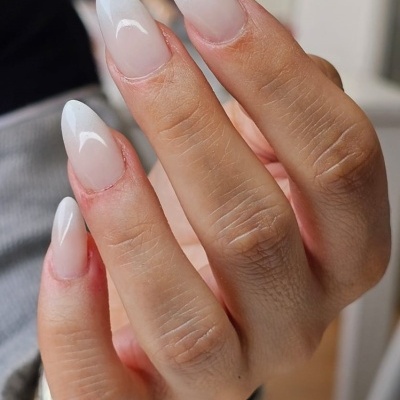 Mão com unhas longas em gel branco perolado ombré
