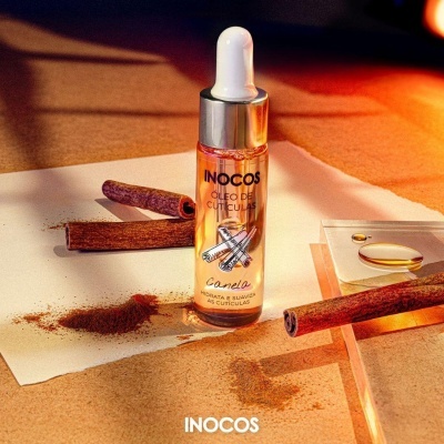 Frasco de óleo de cutículas INOCOS com essência de canela, paus de canela e pó de canela ao redor