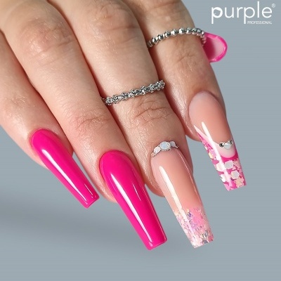 Mão feminina com unhas rosa decoradas e anéis prateados sobre fundo cinzento