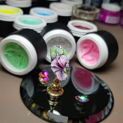 Frascos de gel de unhas coloridos e unha decorada com flor 3D e strass