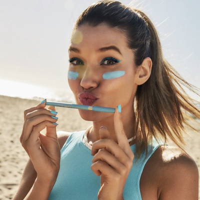 Mulher na praia com lápis de olhos azul claro e maquilhagem azul