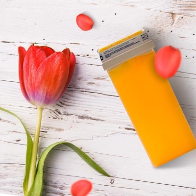 Depilador amarelo ao lado de tulipa vermelha em superfície branca de madeira