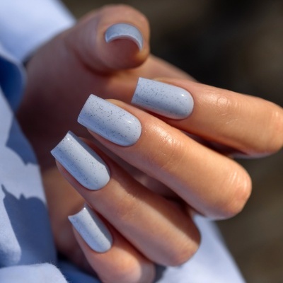 Unhas quadradas pintadas de azul claro com pontos pretos e texto SAUTE NAILS