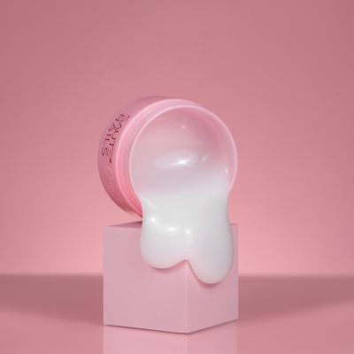 Recipiente rosa de creme escorrendo sobre cubo rosa com fundo rosa