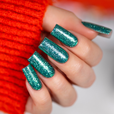 Unhas compridas com esmalte verde glitter e casaco laranja
