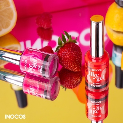 Vernizes de unhas INOCOS Pink e Alive Coral junto a morango e frutas em fundo colorido