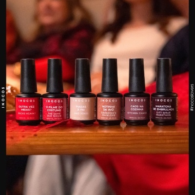 Seis frascos de verniz gel INOCOS em várias cores com rótulos detalhados numa mesa de madeira