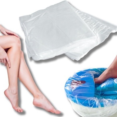 Luvas plásticas transparentes para pés com bacia azul e pernas femininas nuas