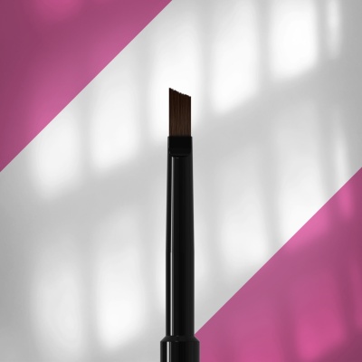 Pincel de maquilhagem preto com cerdas castanhas inclinadas sobre fundo rosa e branco