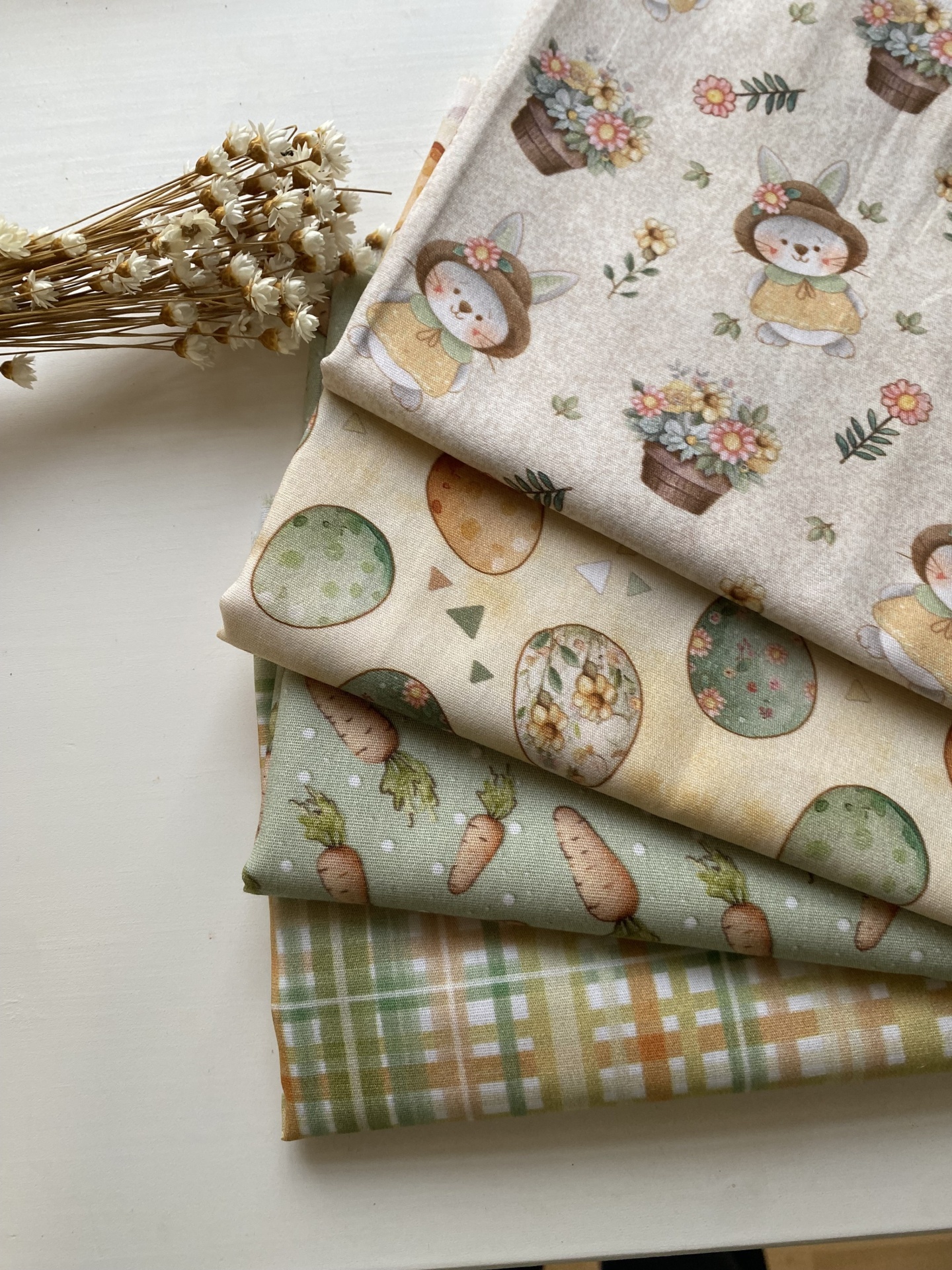 Pack 4 tecidos de algodão Tecidos com padrões de coelhinhos, ovos de páscoa, cenouras e xadrez, junto a flores secas.