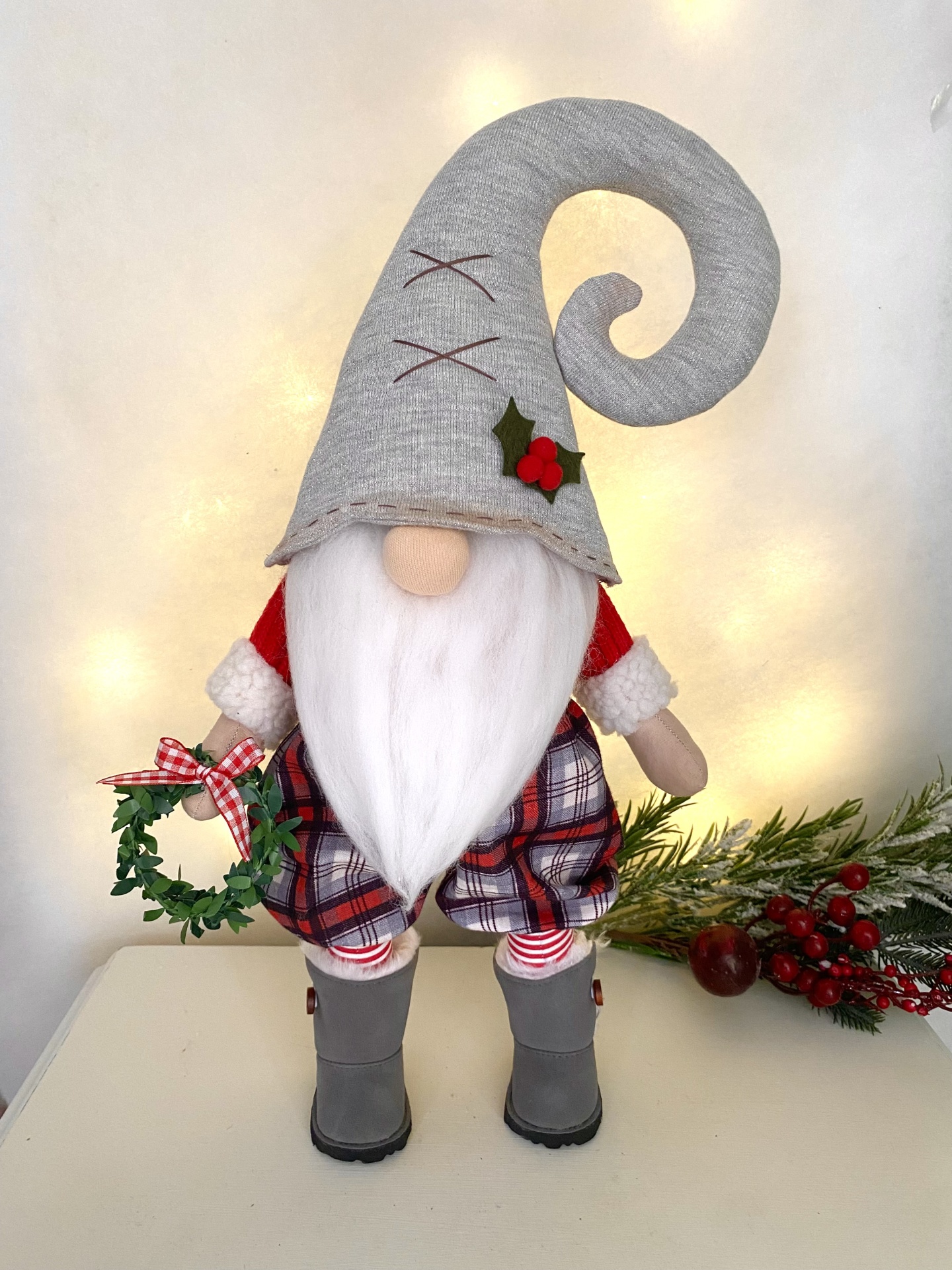 Kit Gnomo de Natal Figura decorativa de Gnomo natalício com chapéu cinza, barba branca, roupa vermelha e calças xadrez segurando grinalda