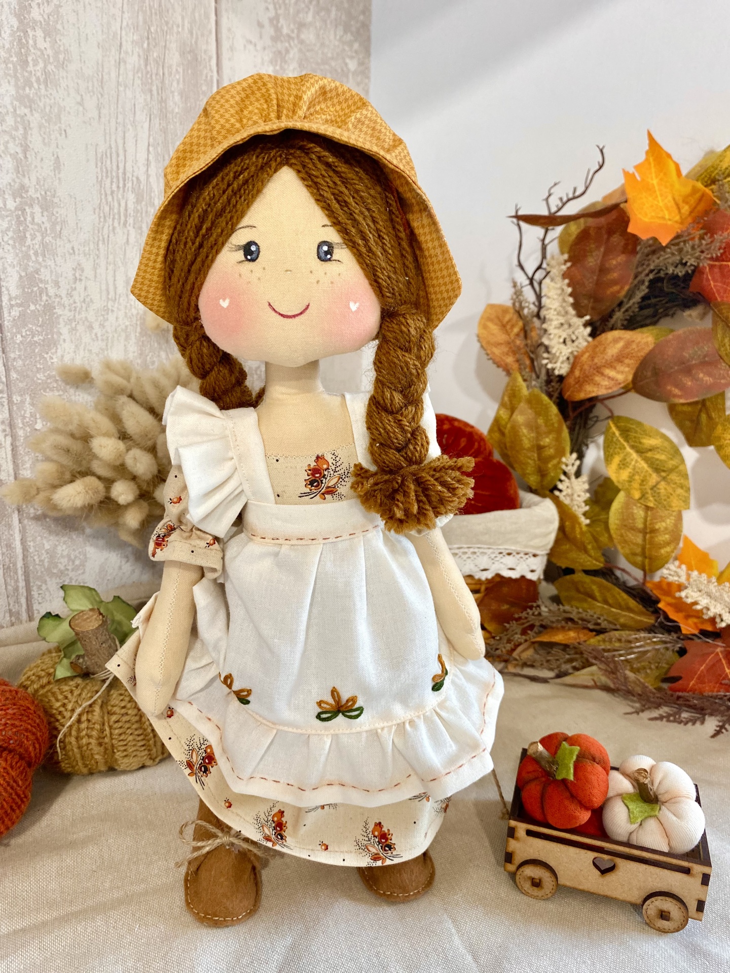 Kit completo com aula gravada- Camponesa Boneca de pano vestida com avental branco e chapéu amarelo num ambiente com decoração de outono