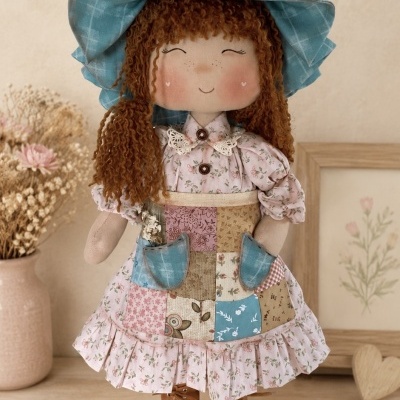 Boneca de tecido vestida com roupa colorida, chapéu azul e botas castanhas