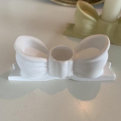 Castiçal branco em forma de laço sobre superfície branca