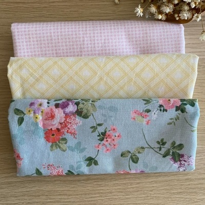 Três pedaços de tecido com padrões diferentes dispostos horizontalmente sobre madeira clara.