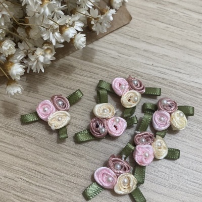 Acessórios florais em tecidos bege, rosa e roxo com folhas verdes