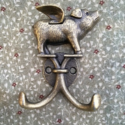 Gancho de parede metálico com forma de porco com asas em fundo floral