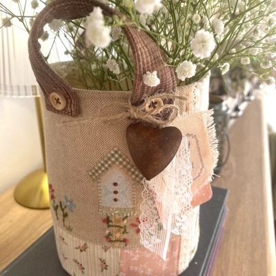 Pote decorativo em tecido patchwork com coração de metal e flores brancas pequenas