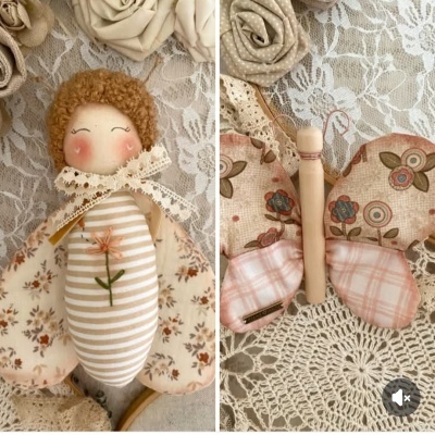 Boneco de pano com vestido às riscas e asas floridas, borboleta de tecido floral e xadrez sobre renda branca
