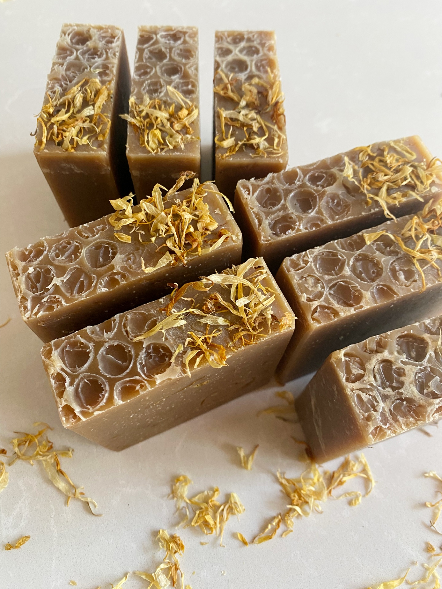 Sabonete natural de calêndula, aveia e mel Barras de sabonete castanho com textura bolha e pétalas secas amarelas