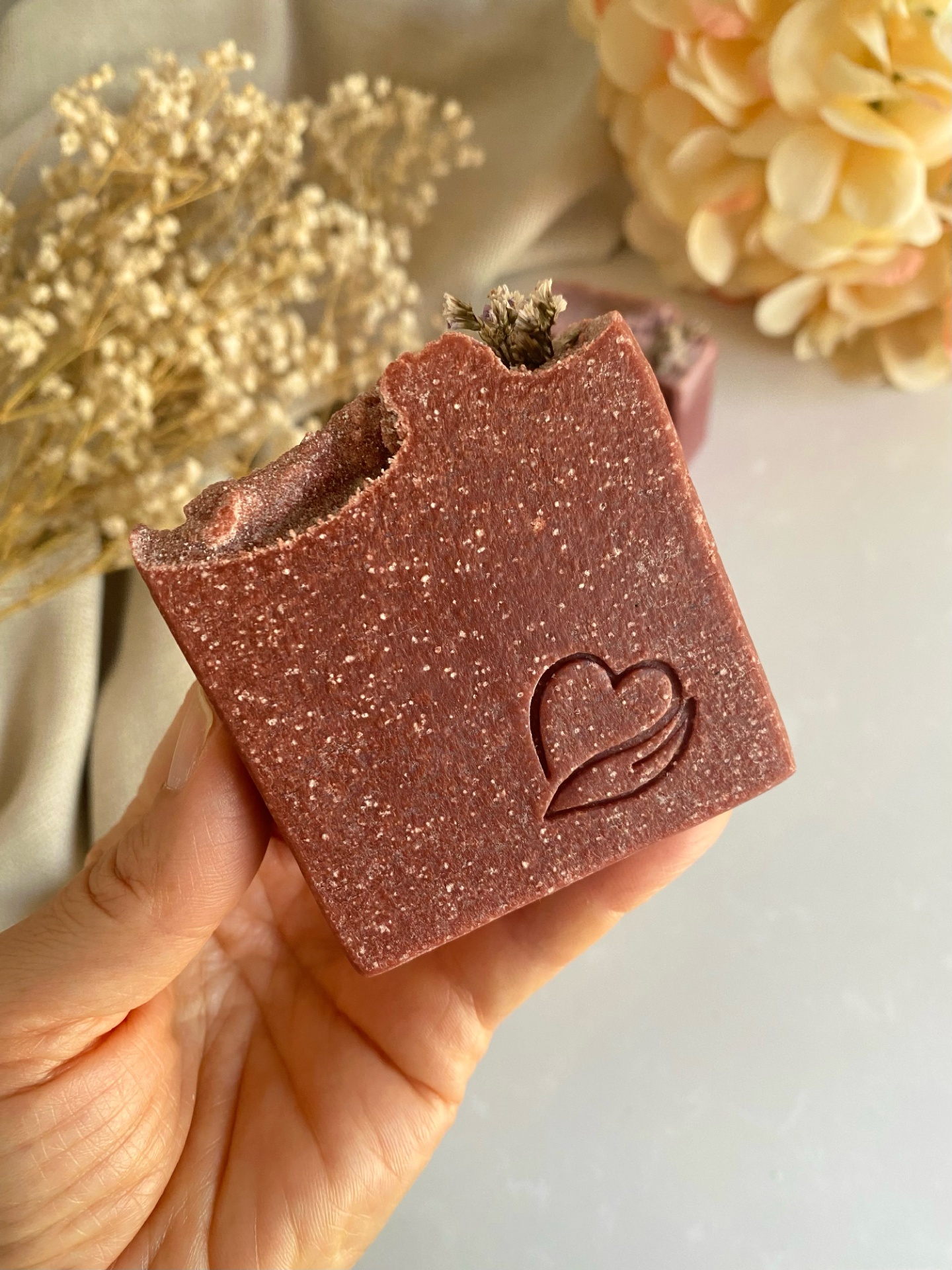 Sabonete natural de vinho rosé Sabonete castanho quadrado com desenho de coração e ramo seco
