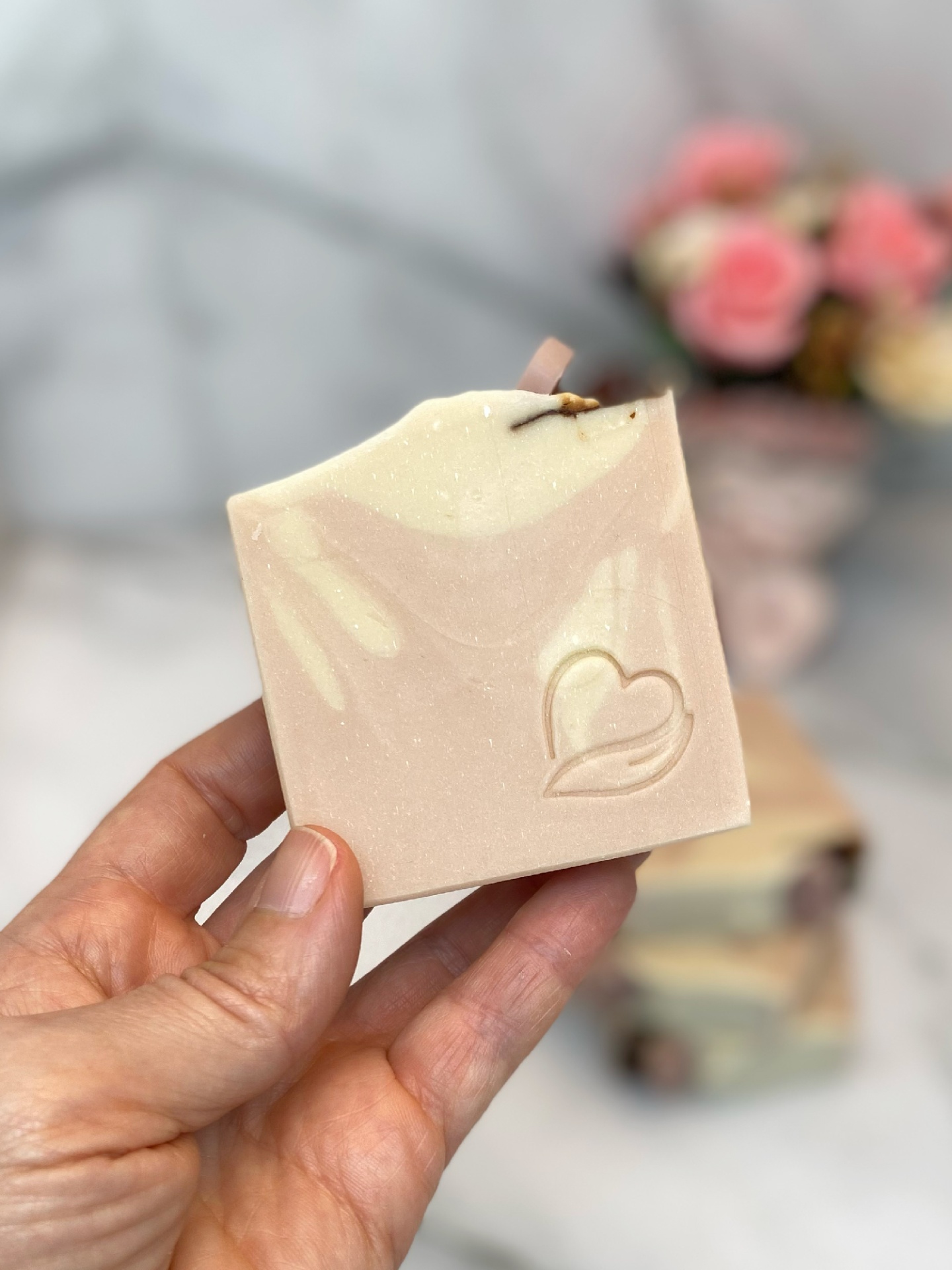 Sabonete natural milky rose Sabonete artesanal bege com relevo de coração segurado por uma mão