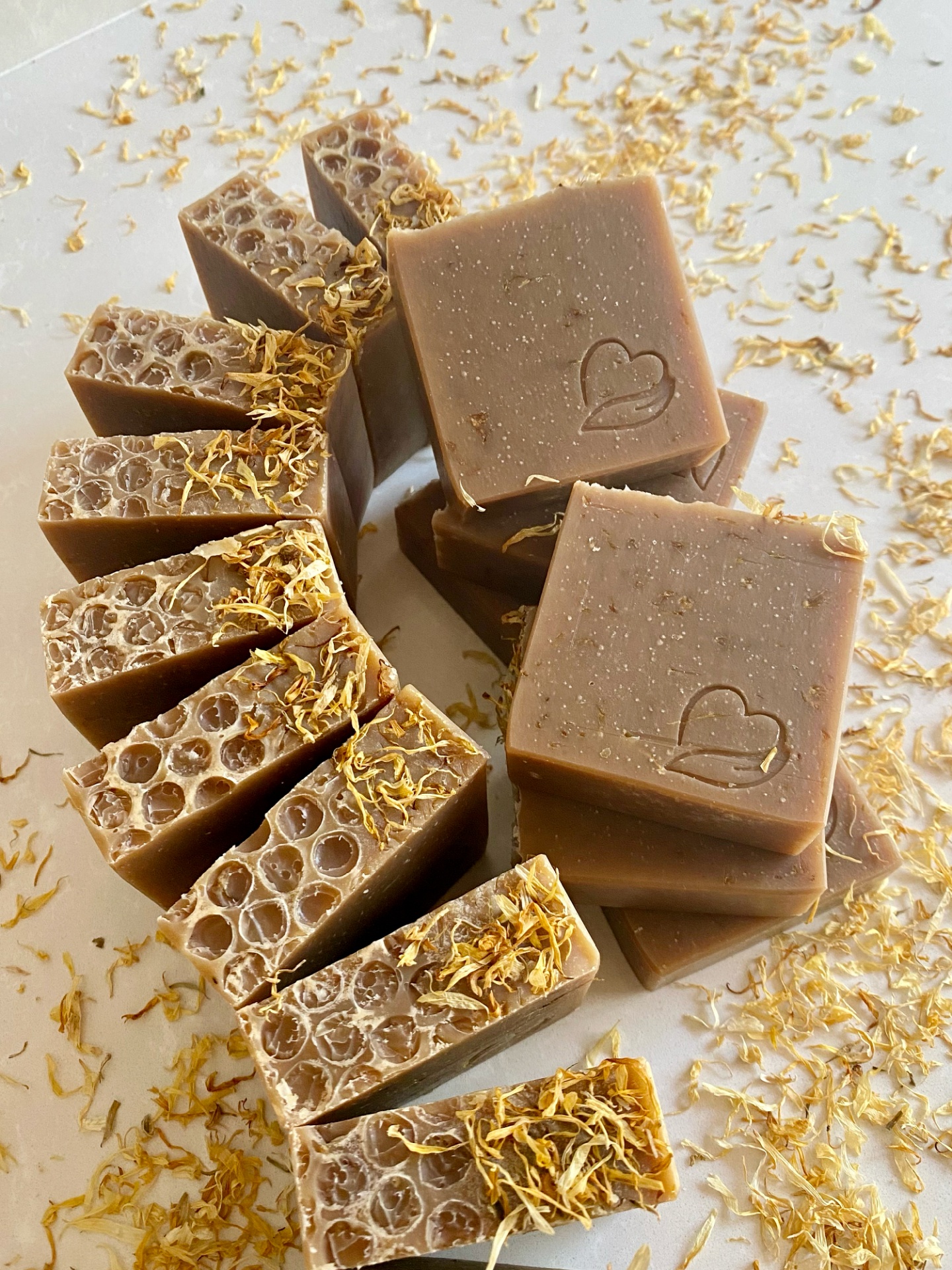 Sabonete natural de calêndula, aveia e mel Sabonetes castanhos com padrão de favo de mel e pétalas secas amarelas
