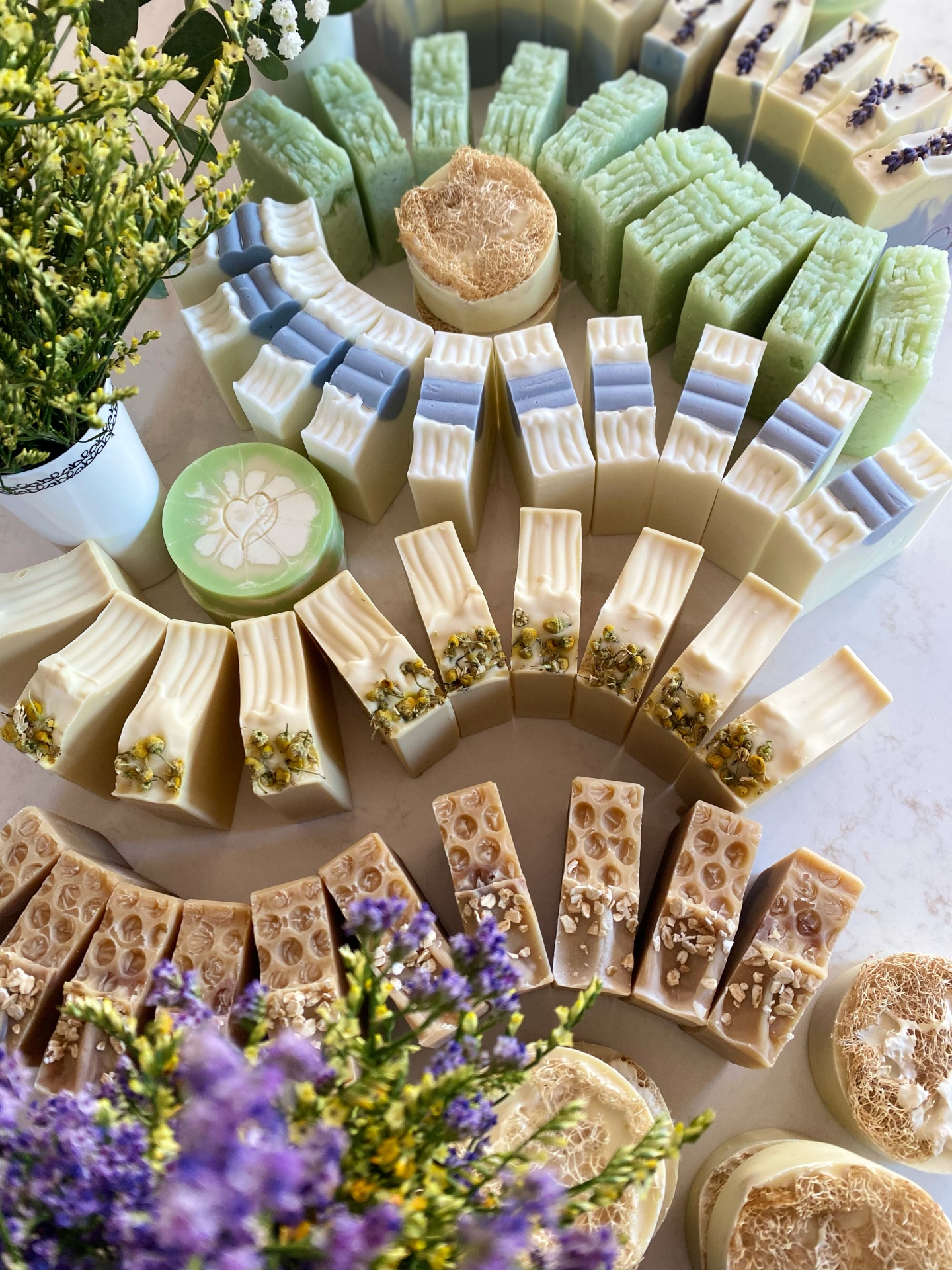 Workshop Sabonetes Naturais Sabonetes artesanais variados com flores secas e loofah em display circular