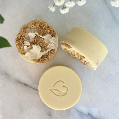 Sabonetes redondos creme com lufa natural e coração gravado numa superfície de mármore