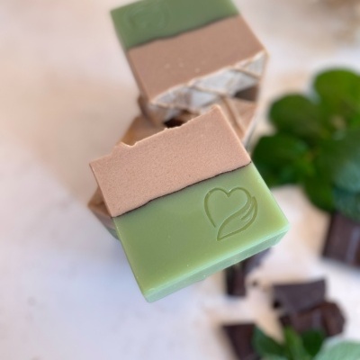 Barras de sabonete artesanal verde e castanho com símbolo de coração e folha gravado.