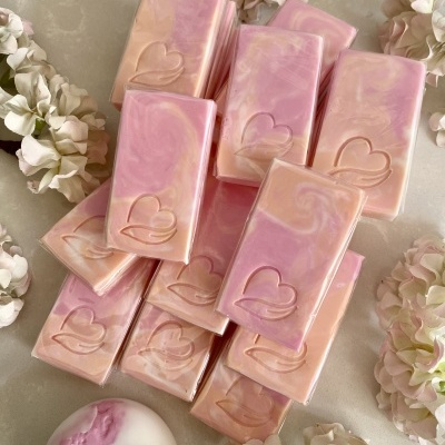 Sabonetes retangulares e redondos rosa e bege com coração gravado e flores ao redor