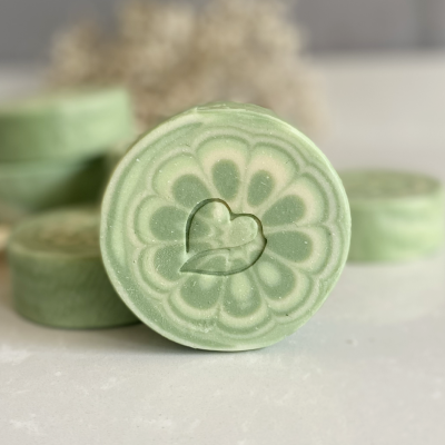 Sabonete verde redondo com desenho floral e coração gravado