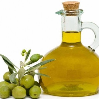 Garrafa de azeite e azeitonas verdes com folhas em fundo branco