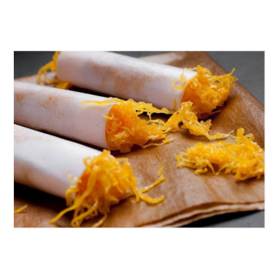 Três palitos brancos com fios de ovos laranja sobre pano castanho.