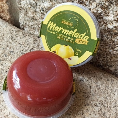Dois recipientes de marmelada sobre pedra, um com tampa visível com rótulo verde amarelo