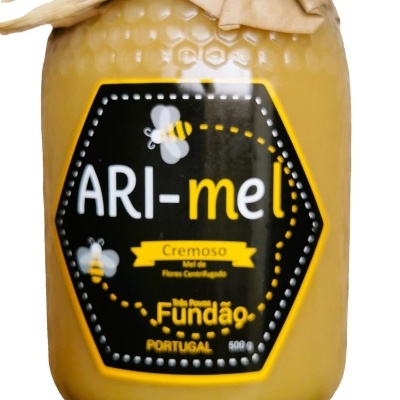 Frasco de mel cremoso ARI-mel com tampa de papel castanho e etiqueta preta com abelhas