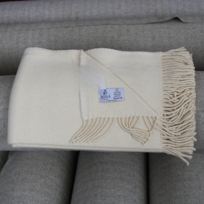 Manta creme de lã de alpaca com franjas sobre sofá cinzento