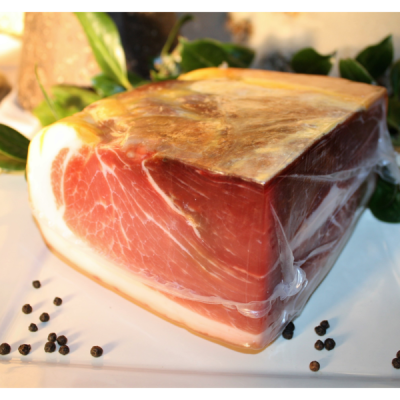 Peça de presunto curado embalada em plástico com pimenta e folhas verdes