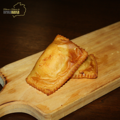 Dois pastéis fritos dourados numa tábua de madeira