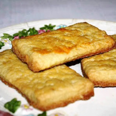 Três biscoitos retangulares dourados numa travessa branca com decoração floral
