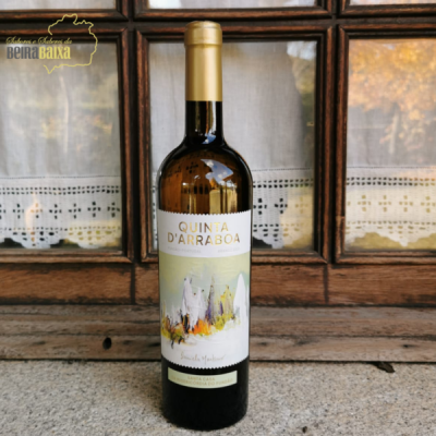 Garrafa de vinho tinto Quinta D'Arraboa com rótulo colorido e rolha dourada à frente de janela com cortinas.