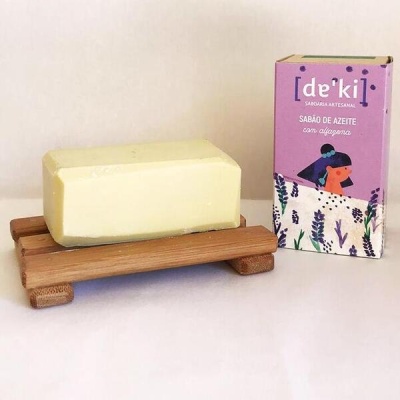 Sabonete amarelo em suporte de madeira com embalagem roxa ao lado